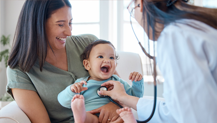 doctor examining baby held by its mother